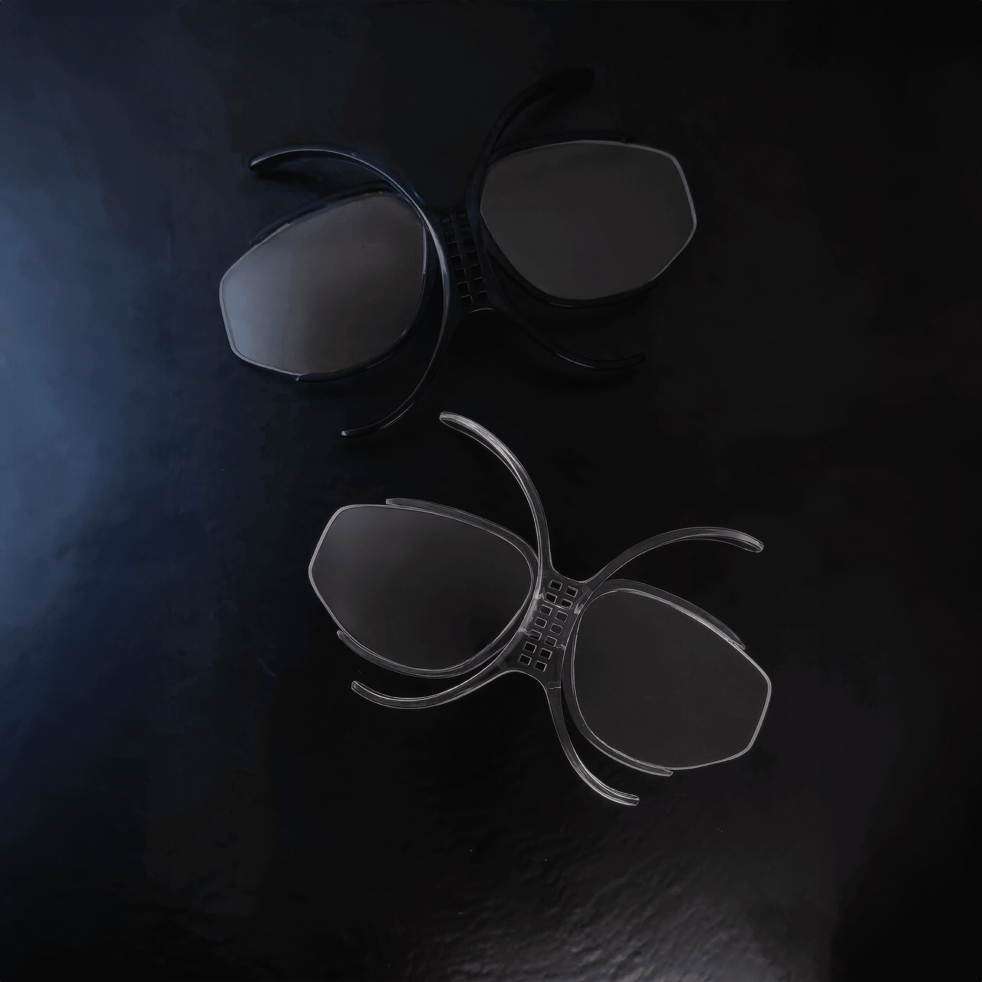 Two CORONET LIFT inserts, one transparent and one midnight blue, on a dark surface.
